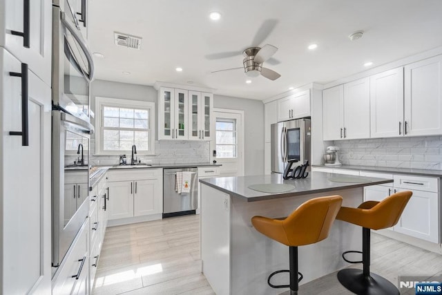 kitchen with stainless steel appliances, a breakfast bar, a sink, visible vents, and white cabinets