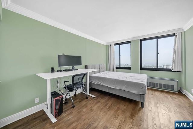 bedroom with ornamental molding, radiator, baseboards, and wood finished floors