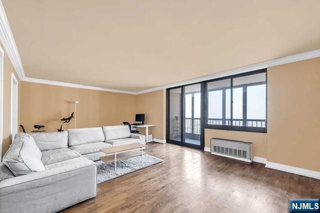 living area with crown molding, baseboards, wood finished floors, and radiator