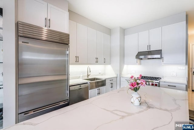 kitchen with under cabinet range hood, white cabinets, stainless steel appliances, and a sink