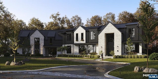 view of front of property featuring a standing seam roof, stone siding, metal roof, and a front yard