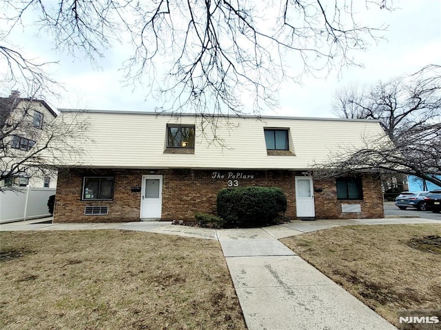 view of property featuring a front yard and brick siding