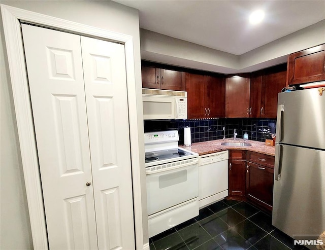 kitchen featuring white appliances, tasteful backsplash, a sink, and dark tile patterned flooring