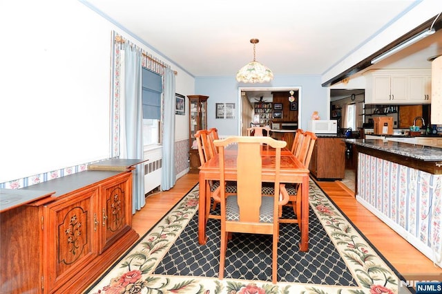 dining room with an inviting chandelier, light wood-style flooring, and ornamental molding