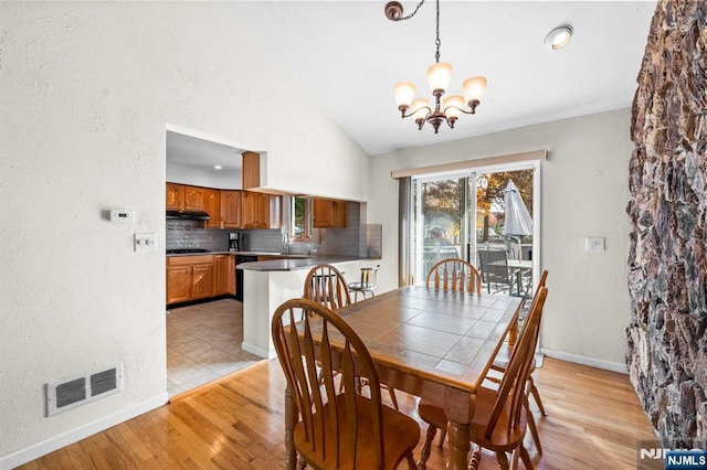 dining room featuring visible vents, vaulted ceiling, light wood-style flooring, and an inviting chandelier