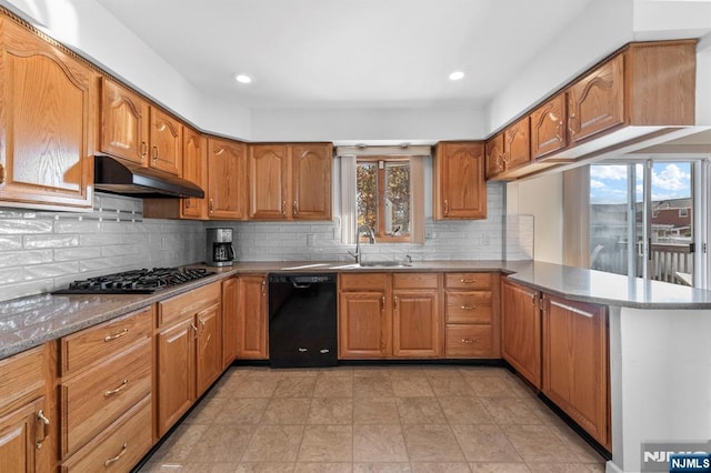 kitchen with under cabinet range hood, a peninsula, gas stovetop, black dishwasher, and brown cabinetry