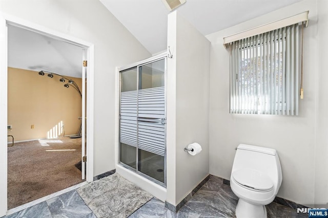 bathroom with toilet, a stall shower, and baseboards