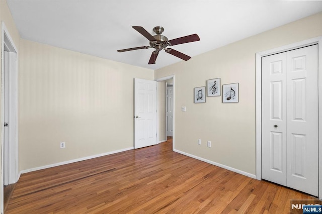 unfurnished bedroom with light wood-type flooring, a closet, ceiling fan, and baseboards