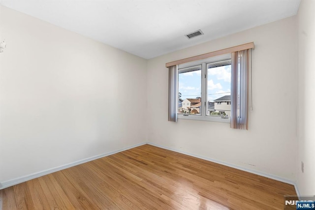 empty room featuring light wood-style flooring, visible vents, and baseboards