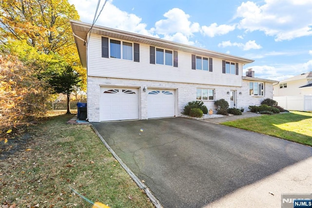 view of front of home featuring driveway, a garage, fence, and a front lawn