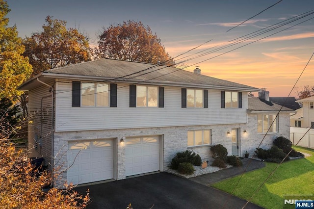 view of front of house featuring driveway, a garage, a chimney, fence, and a front yard