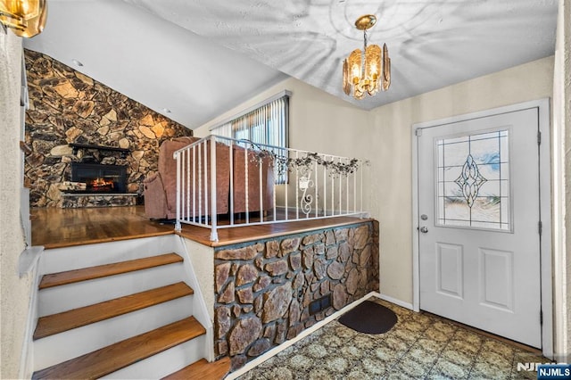 entryway with baseboards, a fireplace, and a notable chandelier