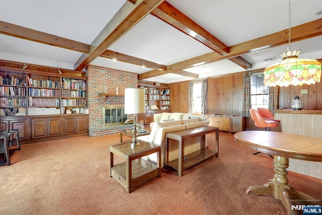 carpeted living room featuring beam ceiling, a brick fireplace, visible vents, and wood walls