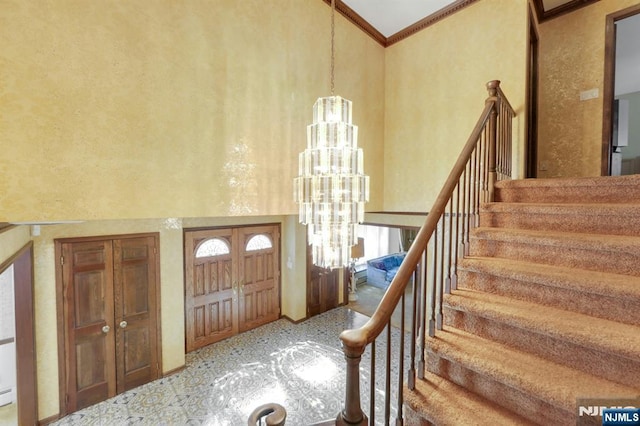 foyer entrance with stairway, an inviting chandelier, a towering ceiling, and crown molding