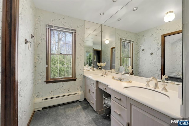 full bath with double vanity, a baseboard radiator, wallpapered walls, and a sink