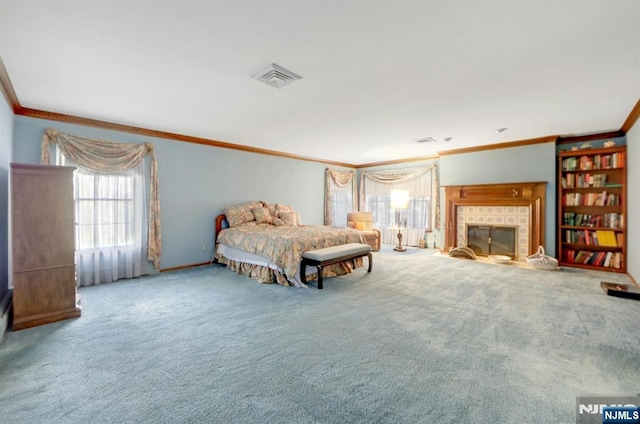 carpeted bedroom featuring visible vents, a tile fireplace, baseboards, and ornamental molding