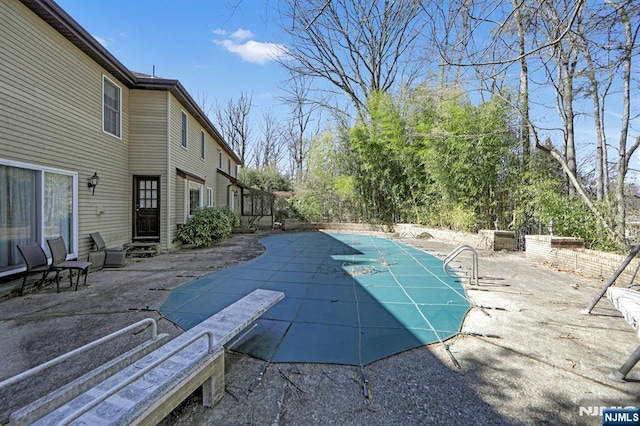 view of pool featuring a covered pool, a patio, and a diving board