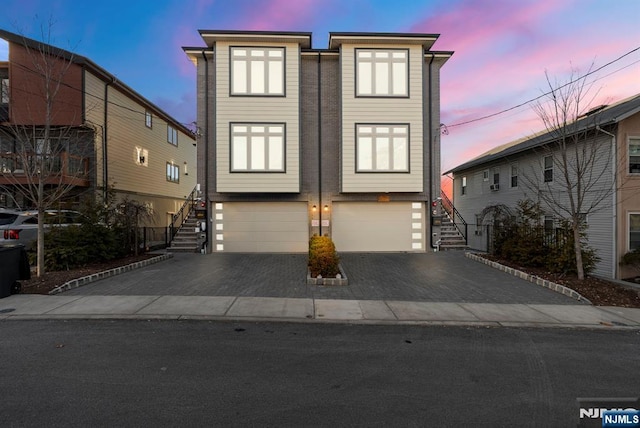 view of front facade featuring a garage, aphalt driveway, and stairway