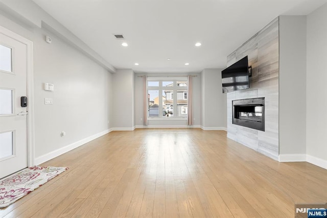 unfurnished living room featuring light wood-style floors, baseboards, a fireplace, and visible vents