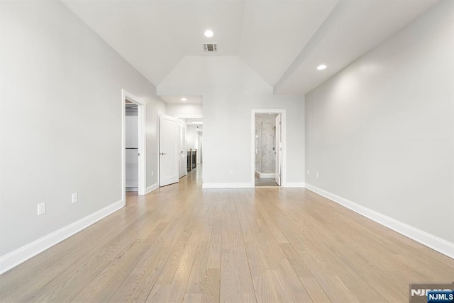 unfurnished living room featuring vaulted ceiling, light wood finished floors, visible vents, and baseboards