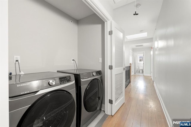 laundry area with laundry area, visible vents, baseboards, independent washer and dryer, and light wood finished floors