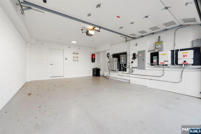 garage with a garage door opener, concrete block wall, and electric panel