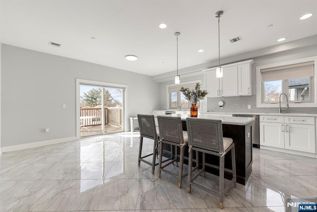 kitchen with visible vents, marble finish floor, light countertops, a center island, and tasteful backsplash