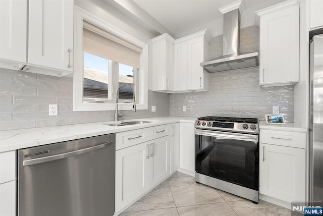 kitchen with stainless steel appliances, a sink, white cabinets, wall chimney range hood, and tasteful backsplash