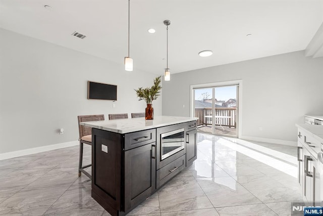 kitchen featuring a breakfast bar area, visible vents, baseboards, marble finish floor, and light countertops