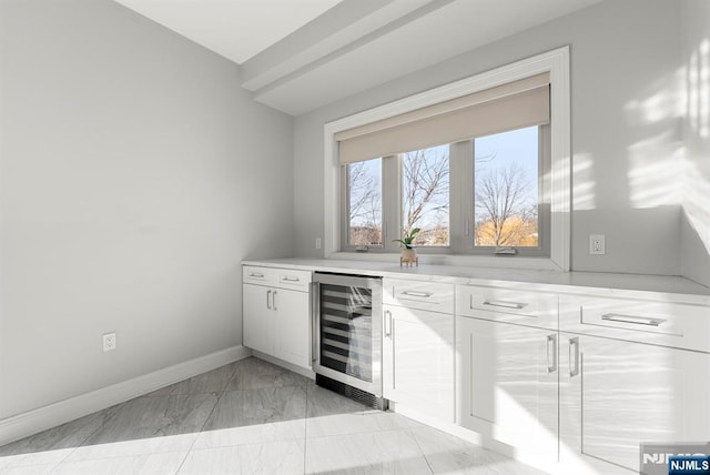 bar with marble finish floor, wine cooler, and baseboards