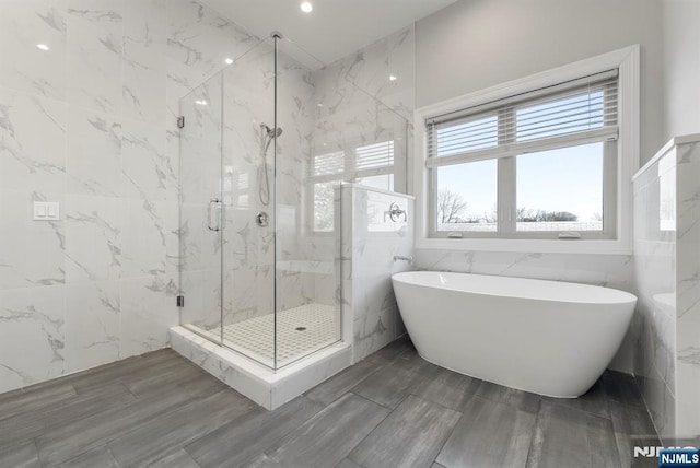 bathroom featuring a soaking tub, tile walls, and a marble finish shower