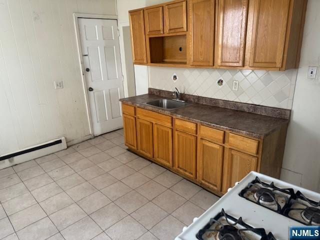 kitchen featuring a sink, backsplash, dark countertops, and baseboard heating