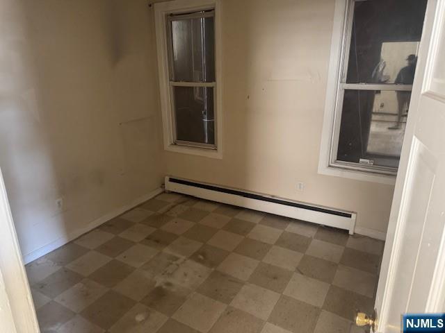 empty room featuring baseboards, baseboard heating, and tile patterned floors