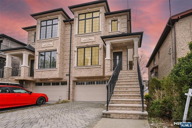 multi unit property featuring driveway, brick siding, and a garage