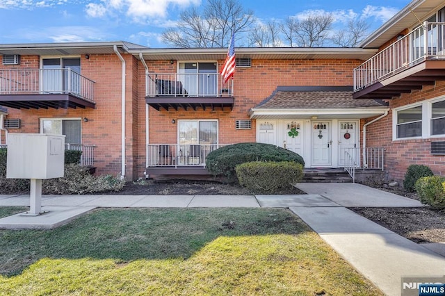 doorway to property with brick siding and a lawn