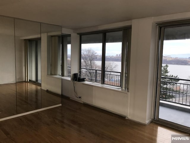 unfurnished room with a water view and wood finished floors