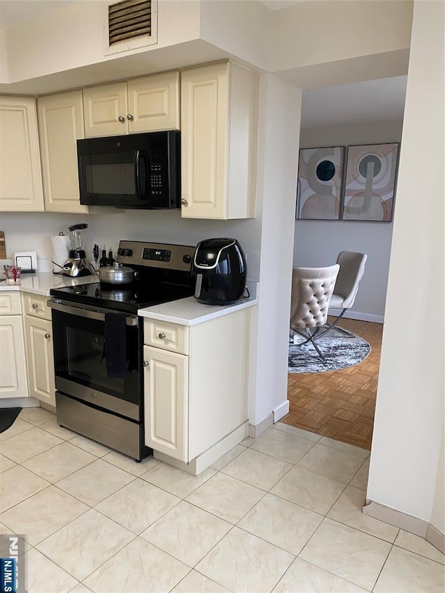 kitchen featuring visible vents, black microwave, light countertops, light tile patterned floors, and stainless steel electric range