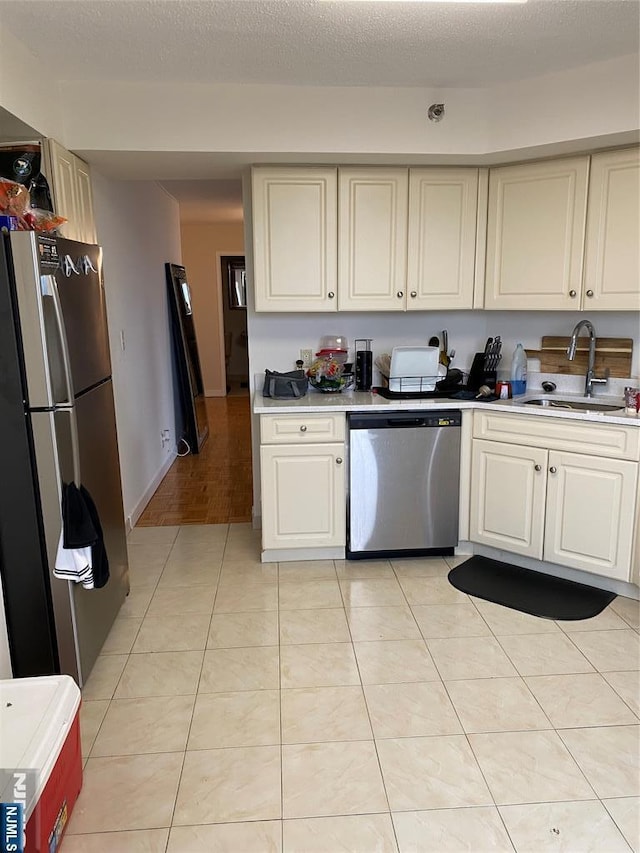 kitchen featuring light tile patterned floors, a sink, stainless steel appliances, light countertops, and a textured ceiling