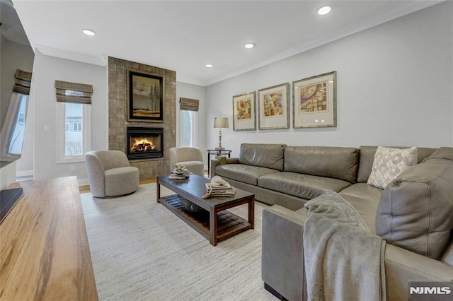 living room with a tiled fireplace, recessed lighting, and ornamental molding