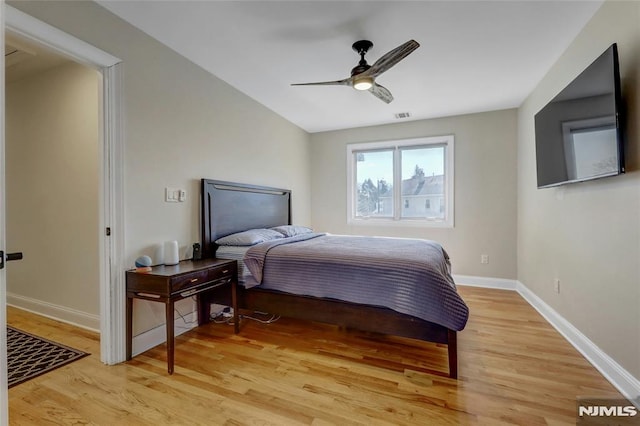 bedroom featuring a ceiling fan, visible vents, light wood-style floors, and baseboards