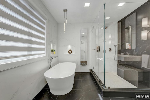 bathroom with a freestanding tub, marble finish floor, a marble finish shower, and a sink