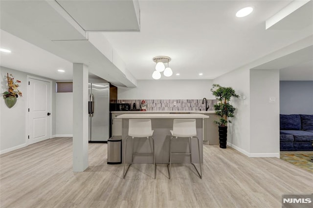 kitchen featuring light countertops, light wood-type flooring, freestanding refrigerator, and a kitchen island