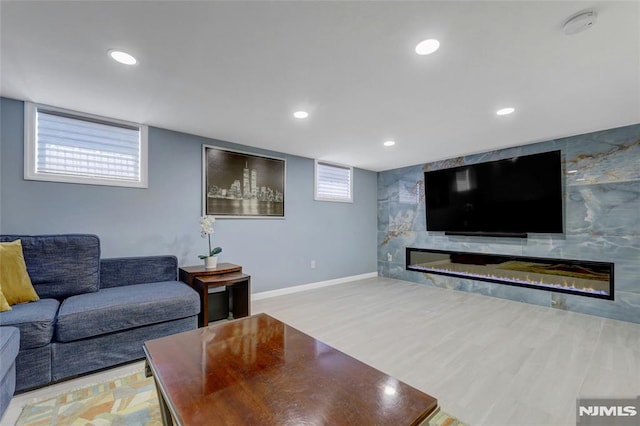 living area featuring recessed lighting, baseboards, light wood-style floors, and a fireplace