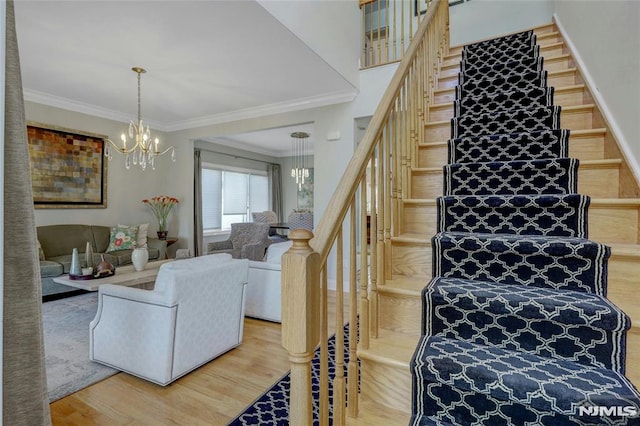 stairway featuring a chandelier, ornamental molding, and wood finished floors