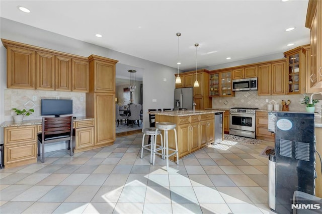 kitchen with light tile patterned floors, built in study area, appliances with stainless steel finishes, pendant lighting, and tasteful backsplash