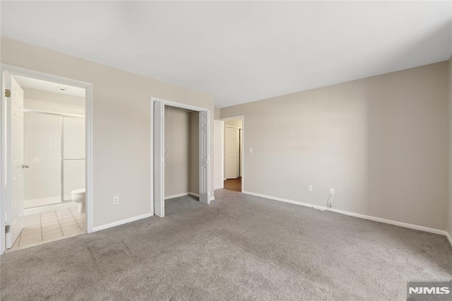 unfurnished bedroom featuring ensuite bathroom, a closet, carpet, and baseboards