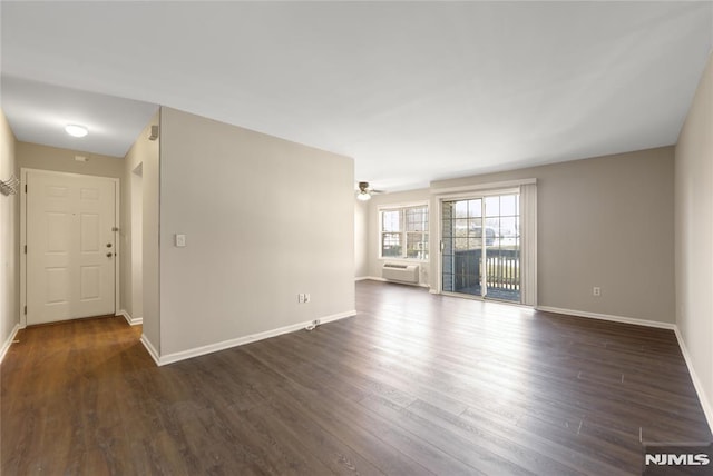 spare room featuring baseboards, dark wood finished floors, and a ceiling fan