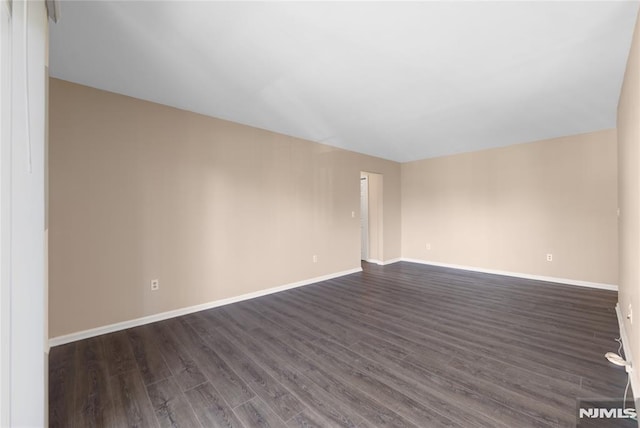 empty room with dark wood-style floors and baseboards