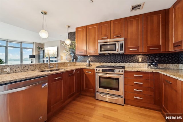 kitchen with light wood finished floors, visible vents, appliances with stainless steel finishes, a sink, and backsplash