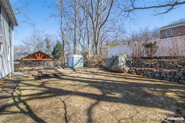 view of yard featuring a storage unit, an outdoor structure, and fence